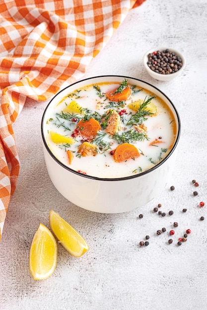 Sopa de salmón cremosa tradicional finlandesa Lohikeitto servida en un tazón blanco Tablero gris claro