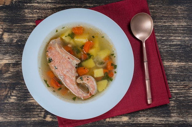 Sopa de salmón fresco con zanahorias y patatas en un plato blanco de cerca