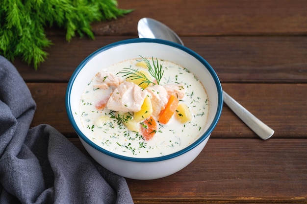 Sopa de salmón con patatas crema, zanahorias y hierbas en un bol sobre un fondo de madera Sopa Lohikeitto