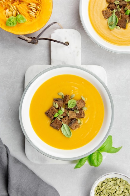 Sopa sazonal de abóbora e cenoura assada no outono com croutons de creme e pão de centeio em um fundo claro de concreto Vista superior