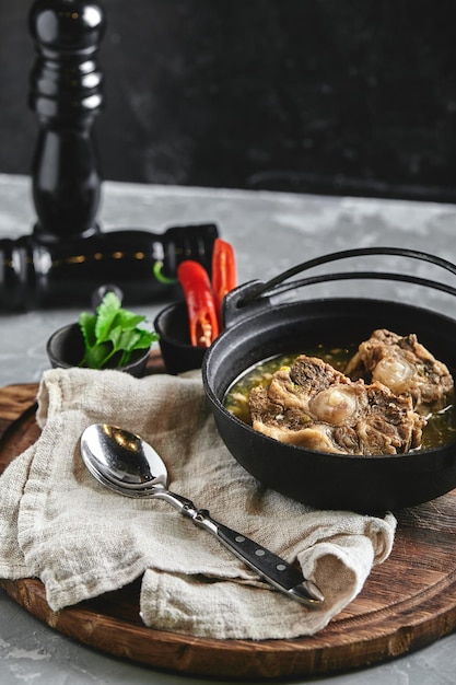 Foto sopa de shurpa en una olla de castirón en la mesa sobre un fondo gris cocina oriental tradicional