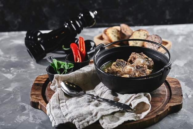 Foto sopa de shurpa en una olla de castirón en la mesa sobre un fondo gris cocina oriental tradicional