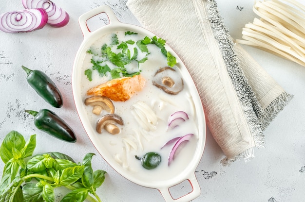 Sopa tailandesa de coco e salmão com ingredientes planos