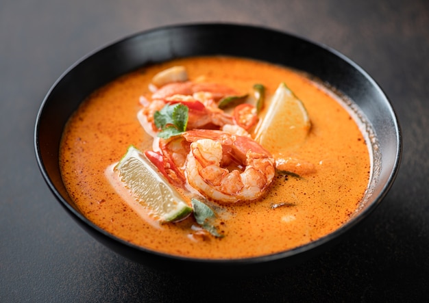 Sopa tailandesa picante tom yum kung com camarão em uma tigela preta em um foco seletivo de fundo escuro