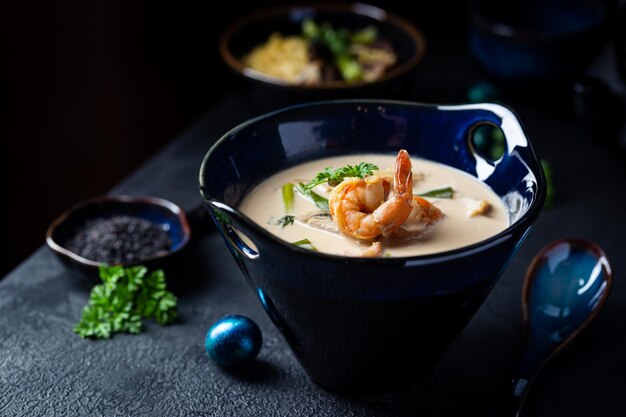 Sopa Tom Yum Kung, una sopa de gambas picante tradicional tailandesa en un bol de fondo oscuro