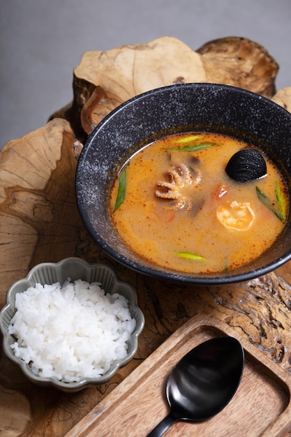 Sopa Tom yum con mariscos y arroz en una mesa de madera