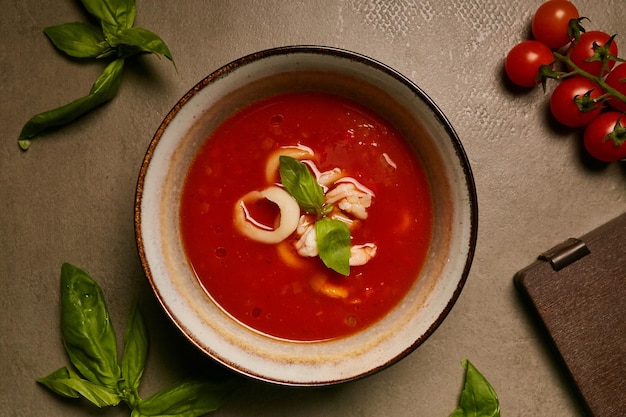 sopa de tomate con calamares en un plato de fondo gris