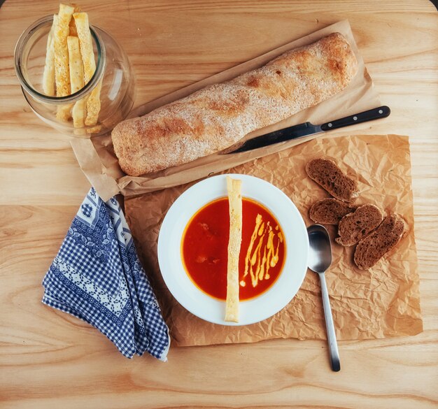 Sopa de tomate fresco en una máscara blanca con baguette de pan