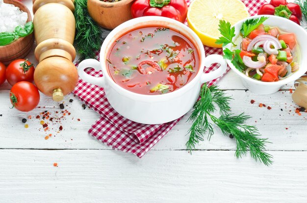 Sopa de tomate con pepino de cebolla y pimentón Vista superior Sobre un fondo de madera blanca Espacio libre para texto