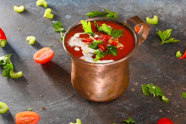 Sopa de tomate rojo en copa de cobre en la oscuridad.