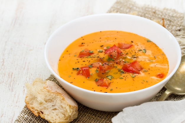 Sopa de tomate en un tazón blanco sobre superficie de madera