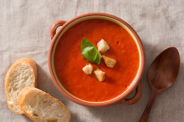 Sopa de tomate en un tazón marrón sobre la mesa de madera. Vista superior