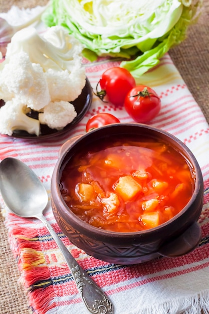 Sopa de tomate vegetariana con repollo y coliflor en un cuenco rústico de cerámica