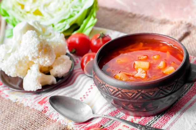 Sopa de tomate vegetariana con repollo y coliflor en un cuenco rústico de cerámica