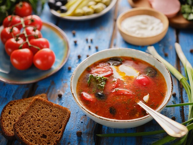 Sopa con tomates, mezcolanza, borscht sobre una mesa azul