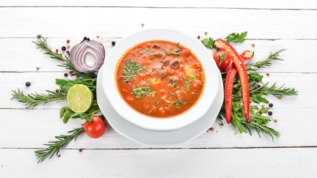 Sopa con tomates de ternera y verduras frescas Sobre un fondo de madera Vista superior Espacio de copia