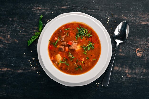 Sopa con tomates de ternera y verduras frescas Sobre un fondo de madera Vista superior Espacio de copia