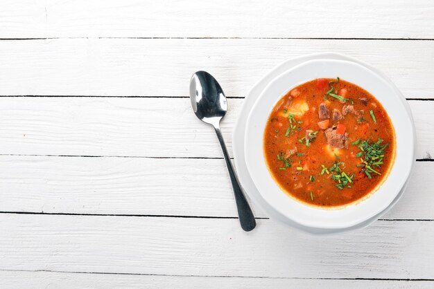 Sopa con tomates de ternera y verduras frescas Sobre un fondo de madera Vista superior Espacio de copia