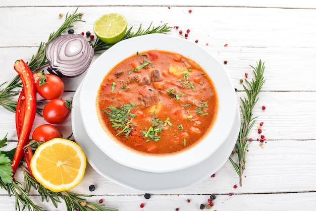 Sopa con tomates de ternera y verduras frescas Sobre un fondo de madera Vista superior Espacio de copia