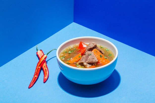 Sopa tradicional asiática, uzbeque, do Oriente Médio com carne ou cordeiro e legumes. Shorpa, sherpa, chorba em azul. Foto de alta qualidade