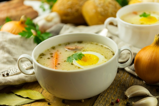 Sopa tradicional polonesa de Páscoa em uma mesa de madeira, com ovo e salsicha