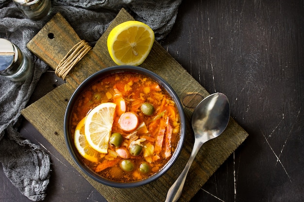 Sopa tradicional russa solyanka com salsichas de carne, legumes, alcaparras, picles e azeitonas