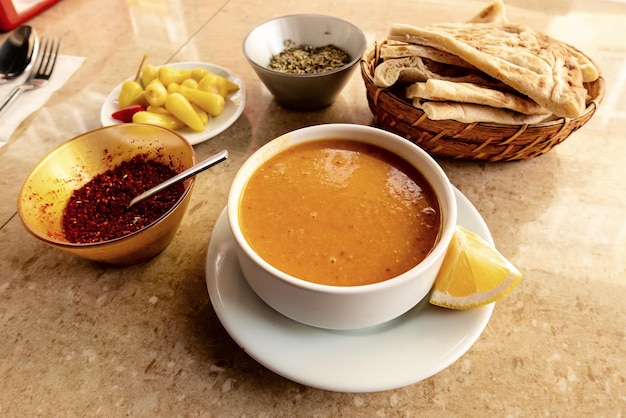 Sopa tradicional turca com lentilhas na mesa com pão e condimentos picantes, fundo alimentar