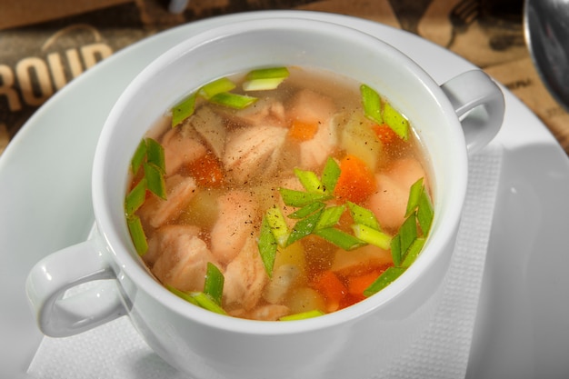 Sopa transparente con pollo, zanahorias y verduras.