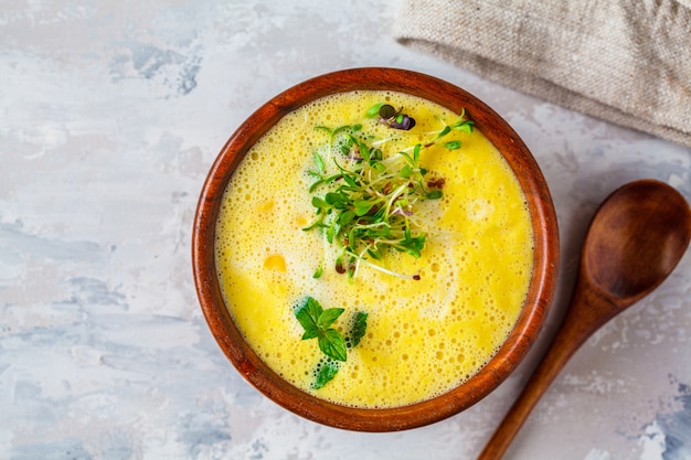 Sopa vegana de crema de maíz en un tazón de madera sobre un gris