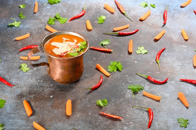 Sopa vegetariana de calabaza naranja en taza de cobre sobre fondo oscuro