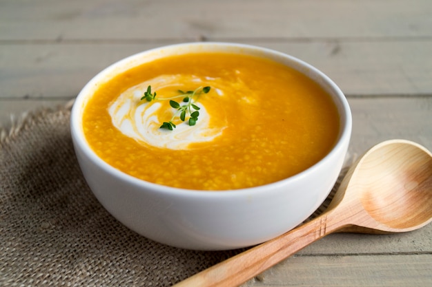 Sopa vegetariana de la calabaza en una tabla de madera.