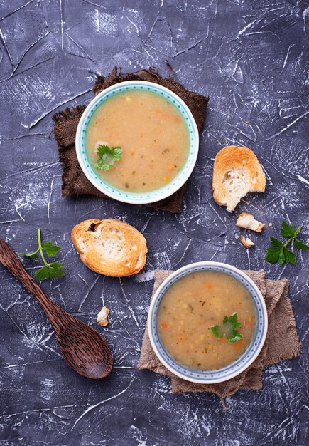 Sopa vegetariana sana de los guisantes en fondo concreto