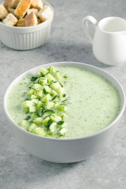 Sopa verde fresca de verano con picatostes de pepino y crema sobre fondo gris concepto de vegano