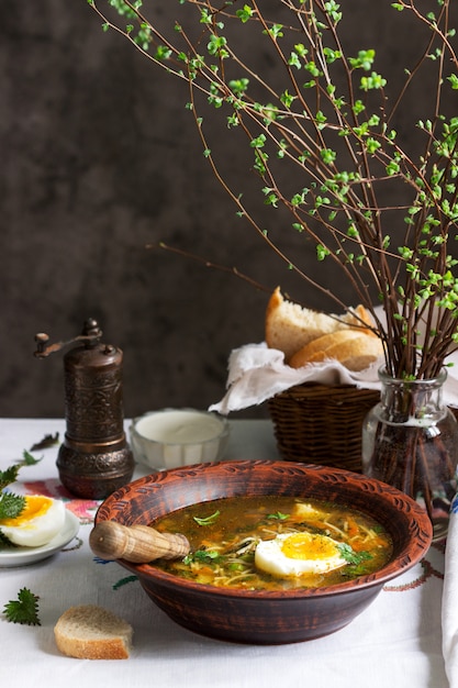 Sopa verde primavera com ervas, legumes e ervilhas, servido com ovo e creme de leite. estilo rústico.