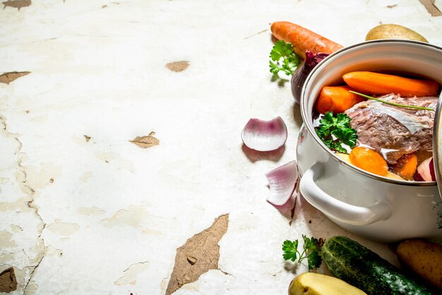 Sopa de verduras, cerdo, especias y hierbas en una cacerola.