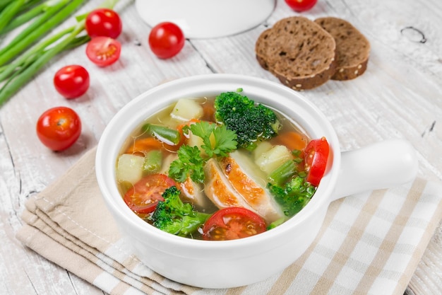 Sopa de verduras con cuenco de cerámica blanca de pollo