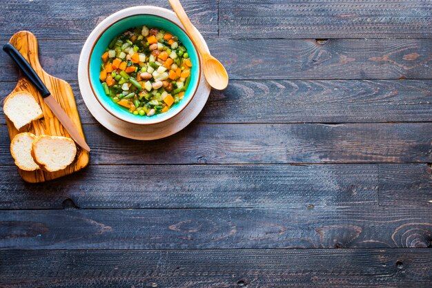 Sopa de verduras frescas hecha en casa, en mesa rústica de madera, vista superior