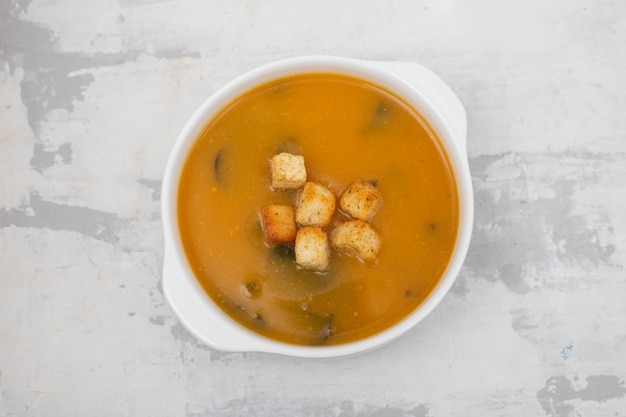 Sopa de verduras con galletas en un tazón blanco sobre cerámica