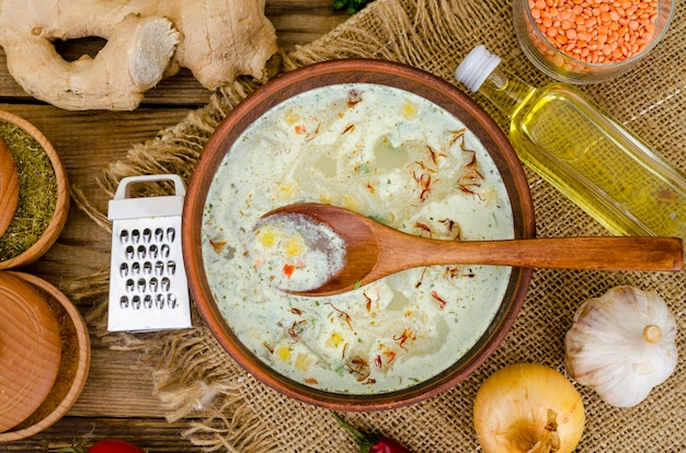 Sopa de verduras con lentejas en recipiente de arcilla en la mesa