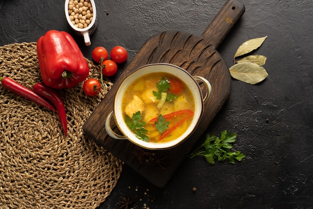 Sopa de verduras con salmón, patatas y pimientos dulces aderezada con hojas de laurel de perejil y tomates cherry.