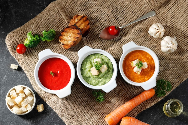 Sopa de verduras de tres colores brócoli tomate zanahoria sobre mesa de mármol negro