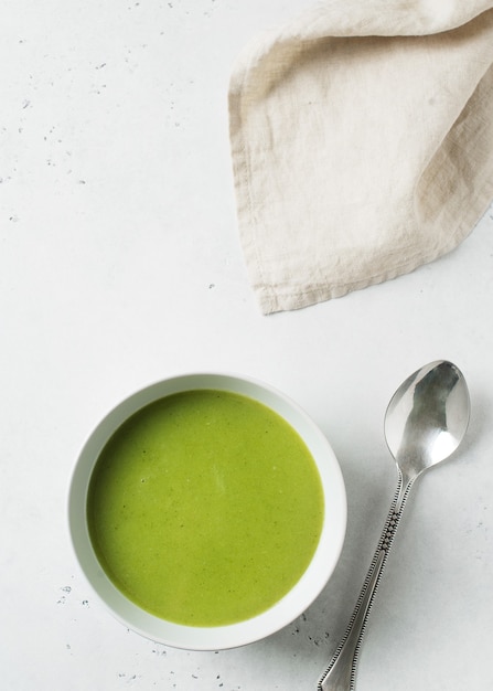 Sopa de verduras verde sobre blanco, vista superior vertical