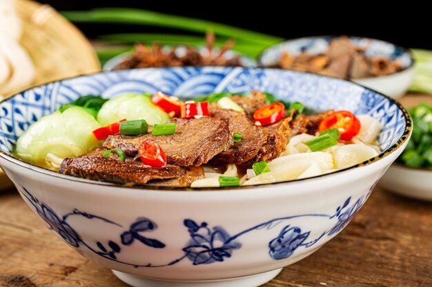 Sopa vermelha de macarrão com carne picante em uma tigela na mesa de madeira