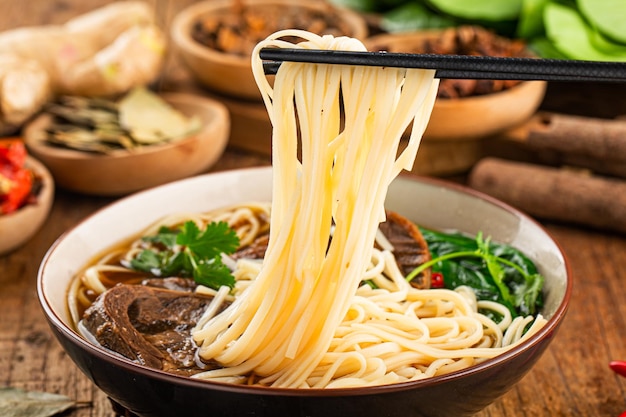 Sopa vermelha de macarrão com carne picante em uma tigela na mesa de madeira