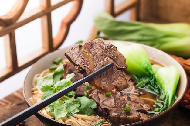 Sopa vermelha de macarrão com carne picante em uma tigela na mesa de madeira