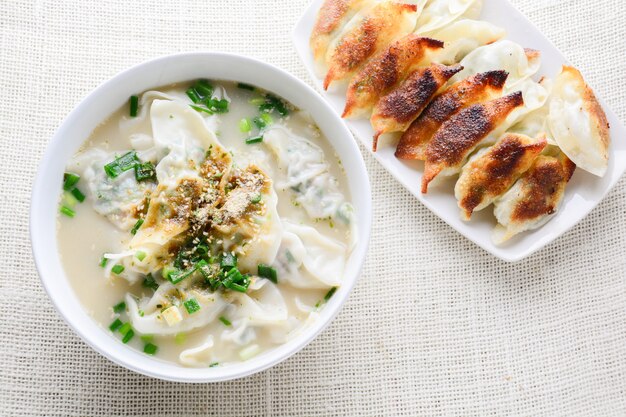 Sopa de wonton con cebolla tierna servida en un tazón blanco, enfoque selectivo