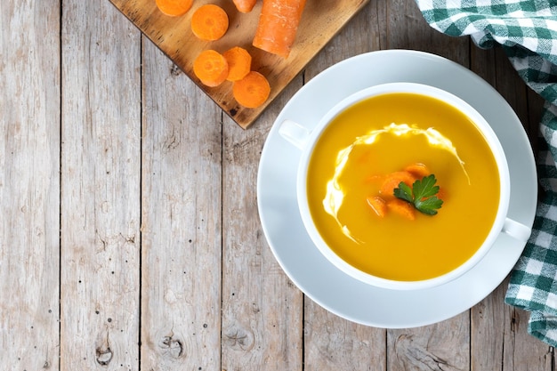 Sopa de zanahoria con crema y perejil sobre mesa de madera Cerrar