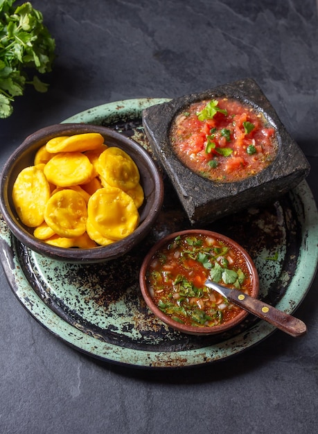 Foto sopaipilla comida latinoamericana sopaipillas tradicionales chilenas caseras de calabaza con salsas típicas chancho en piedra salsa de tomate en mortero de piedra y pebre picante