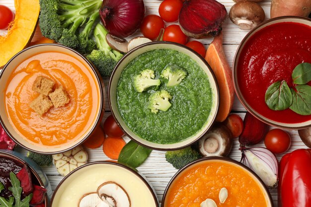 Foto sopas de legumes e ingredientes em branco de madeira, vista superior