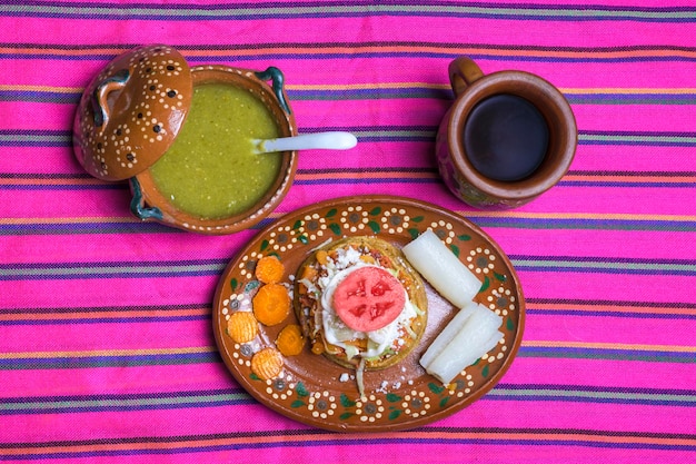 sope comida mexicana tradicional servida em um prato de barro em um fundo colorido